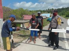 Cegah Covid 19, Bhabinkamtibmas Lorulun Bersama Warga Memasang Palang Pada Pintu Masuk Desa