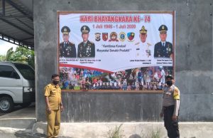 Bersama Warga Pasang Spanduk Hari Bhayangkara ke-74, Bhabinkamtibmas Sifnana sampaikan New Normal