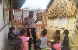 Aipda J. I. M. Manullang melaksanakan program belajar anak sambil membaca melalui perpustakaan Bhabinkamtibmas